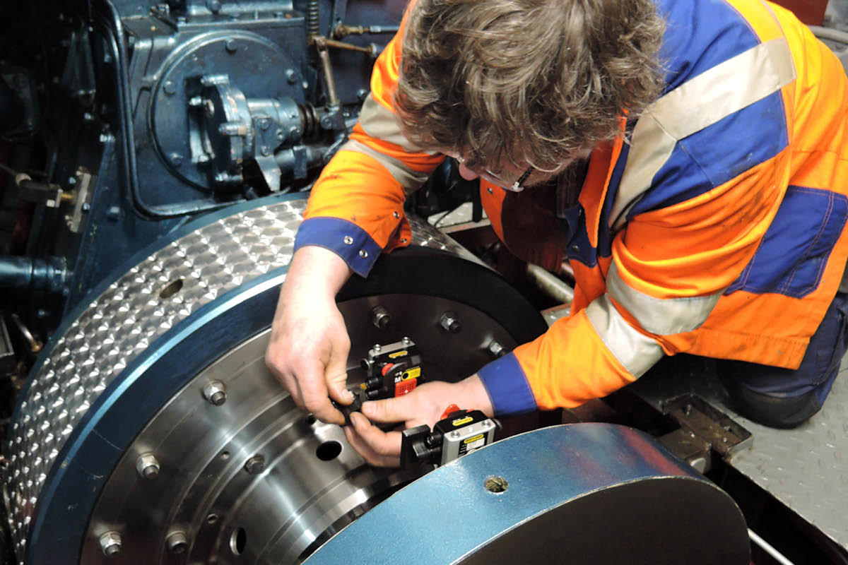 Man bending over machine parts to mount measuring units
