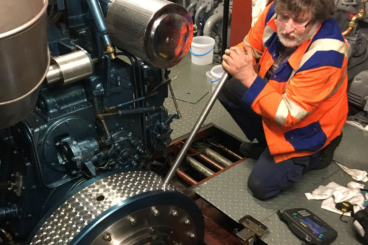 Olaf holding a metal pole that is used to turn a big flywheel